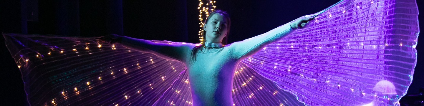 Meisje dansend in vlinderkostuum met verlichting